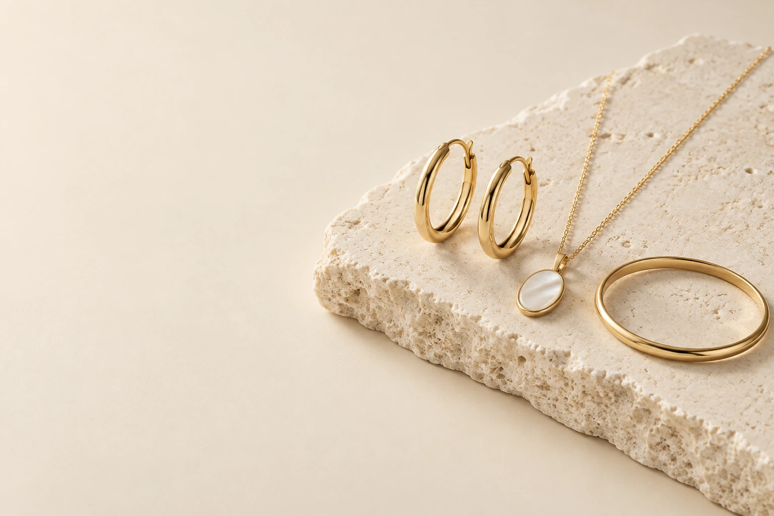 Gold-tone hoop earrings, mother-of-pearl pendant and bangle on ivory stone