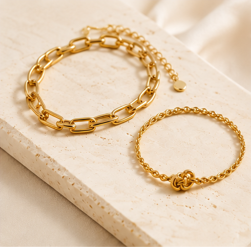 Gold-tone chain bracelets displayed on a cream stone surface