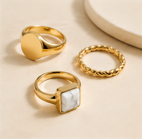 Gold-tone signet, stone and textured rings on a beige background