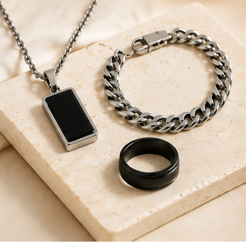 Men’s pendant necklace, chain bracelet and black ring on a stone surface