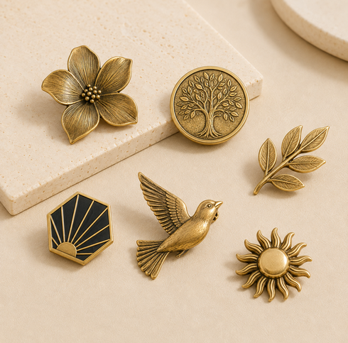 Custom brass brooches, badges and engraved medallions on a warm beige background