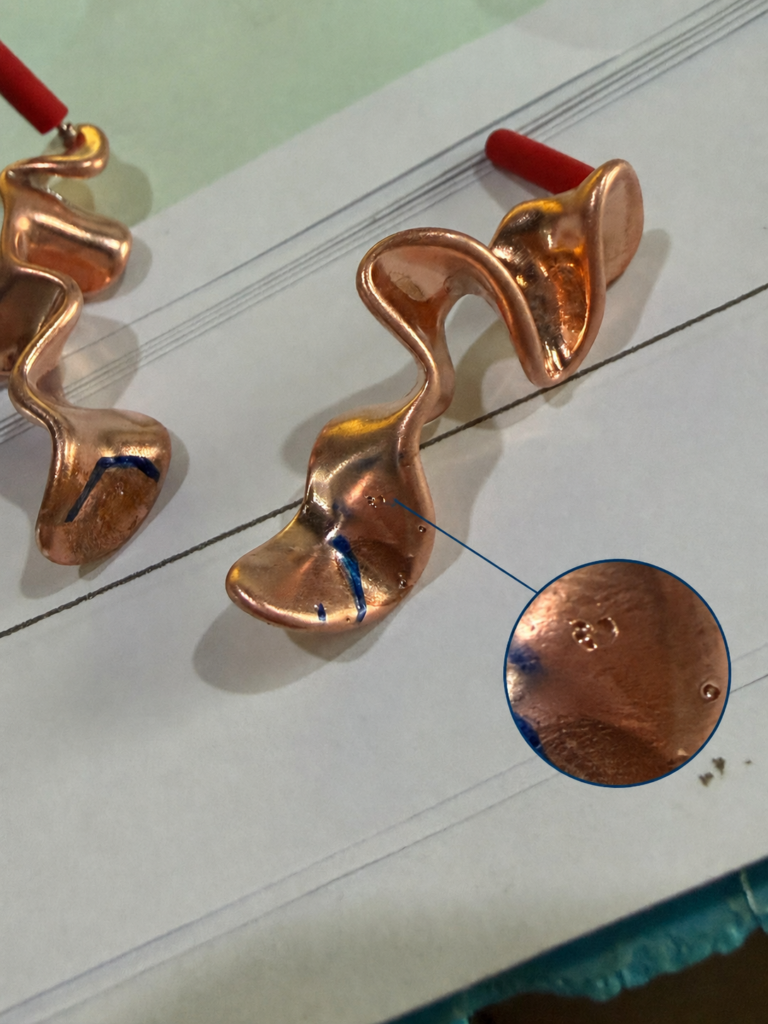 Close-up of an earring casting defect showing small pinholes on the metal surface, which can affect polishing, plating quality and final jewelry appearance.